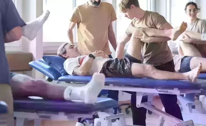 un patient et le physiothérapeute qui effecture une manipulation de la jambe