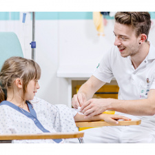 Un infirmier sourit à une petite fille en lui posant un pansement