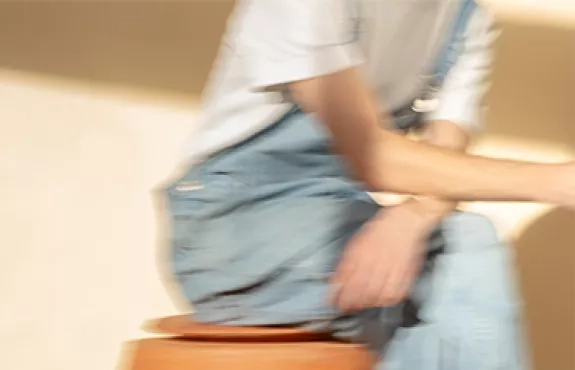 Une personne est assise sur un tabouret, l'image est floue