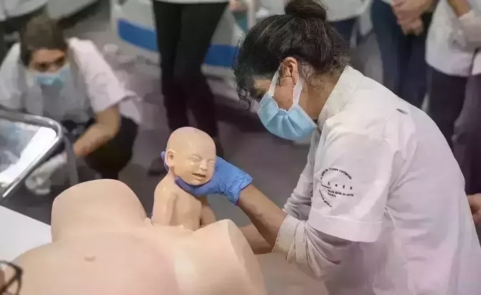une sage-femme assistant l'accouchement d'un mannequin en tant que démontration