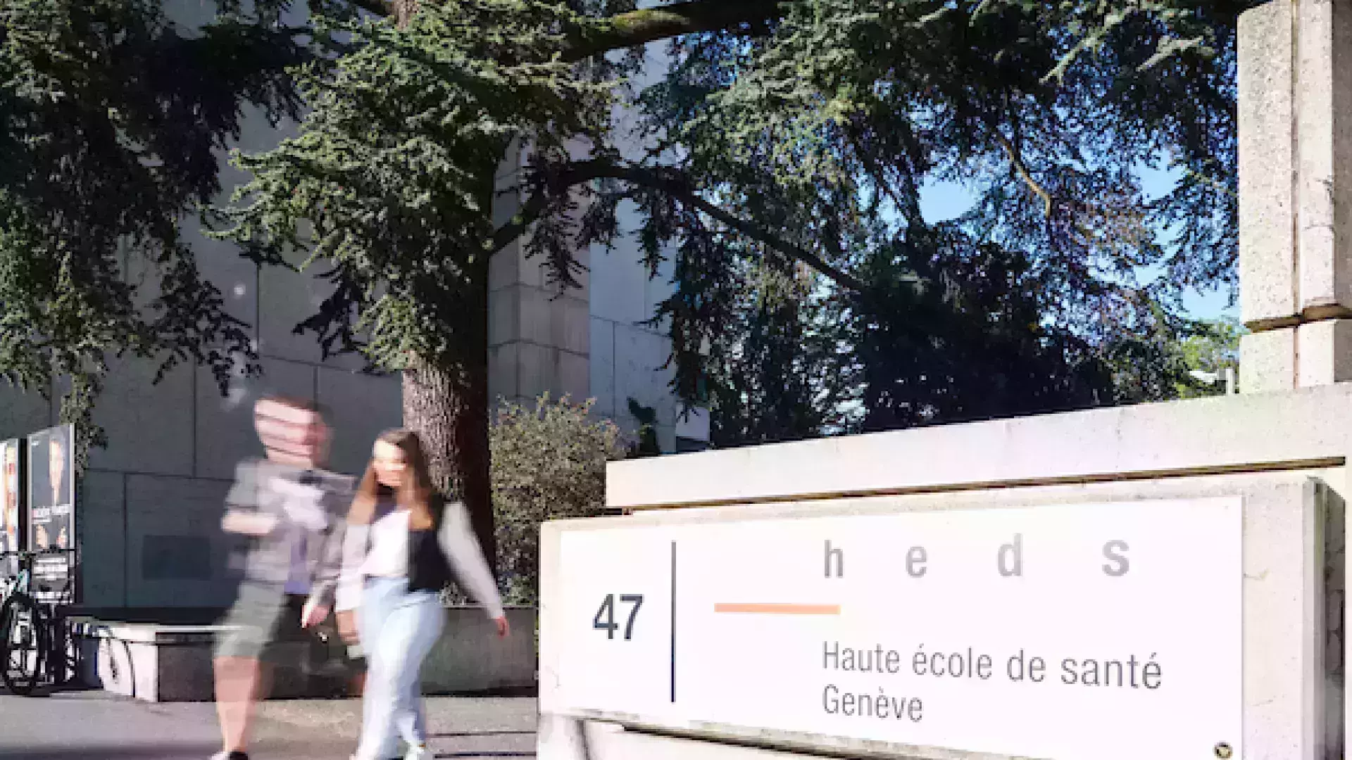 Photo de l'avenue de Champel avec deux étudiants qui marchent devant l'école. Il y a une grosse pancarte avec le logo et le nom de l'école.