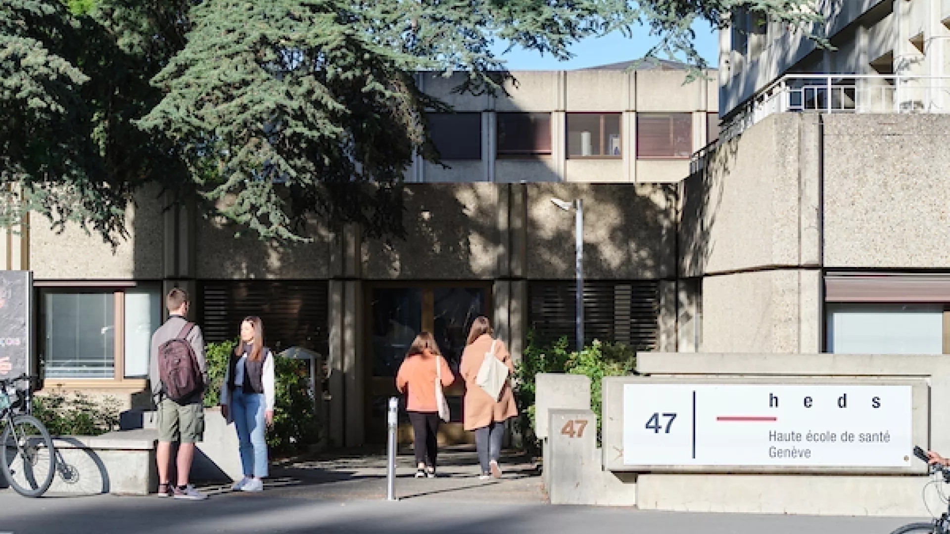 Photo de l'entrée principale de la Haute école de santé de Genève avec des étudiants qui entrent et qui discutent