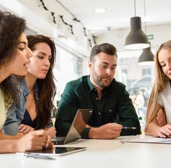 cinq adultes travaillent ensemble autour d'une table sur une thématique de formation continue