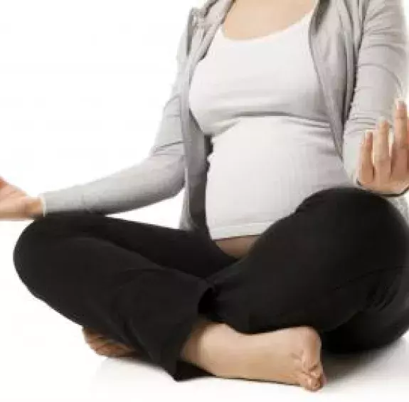 Photo d'une femme enceinte qui médite avec les jambes croisées