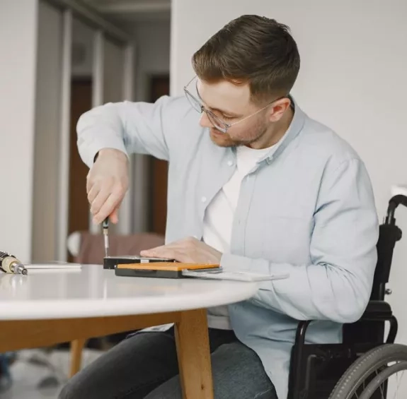 Ergothérapie : jeune homme en chaise roulante qui utilise un tournevis
