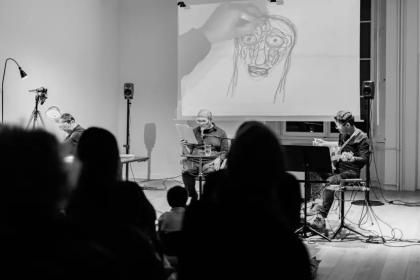 Photo lors de la performance d'une oeuvre pour guitare, récitant et dessinatrice