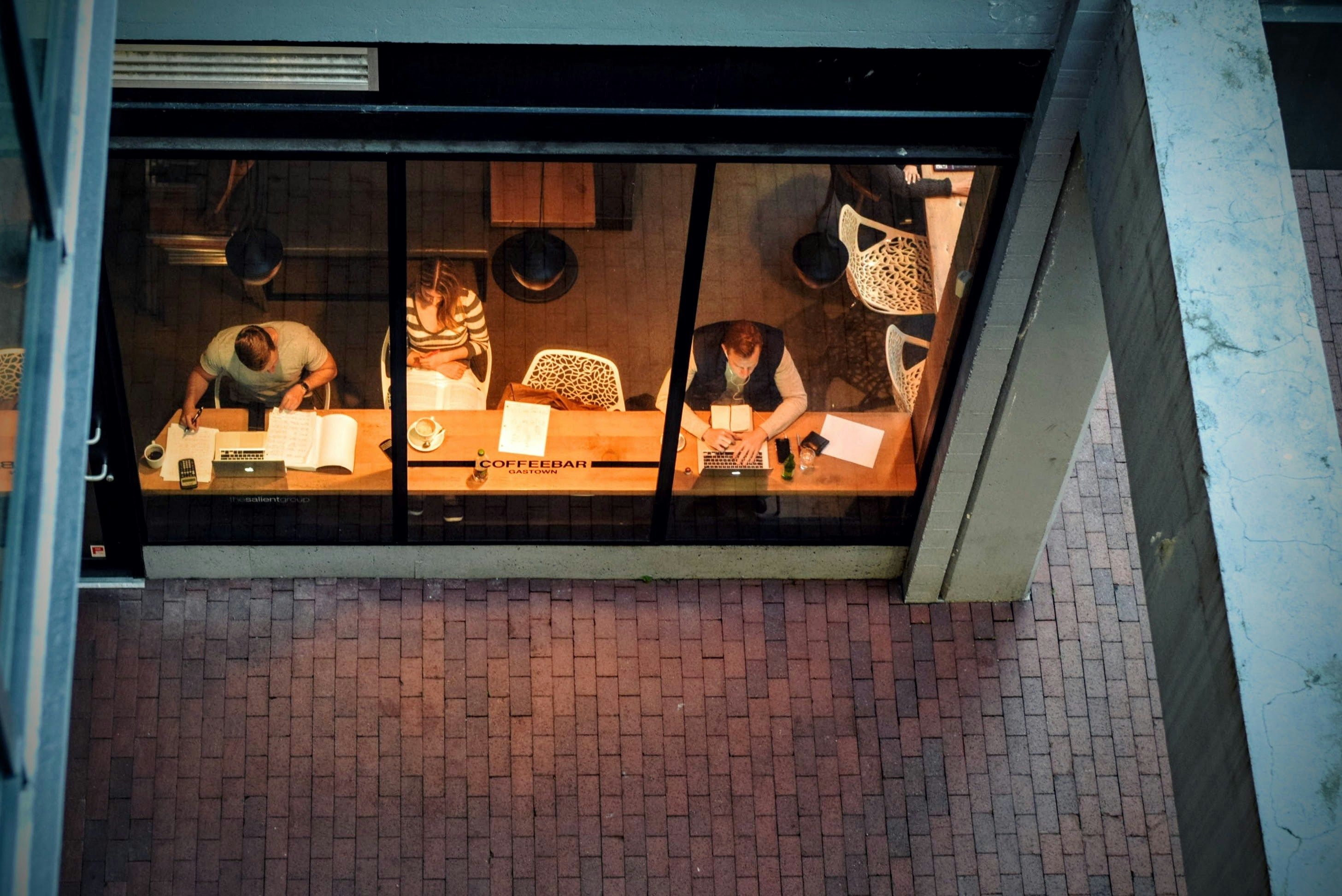 Photo vue de haut de 3 personnes en train de travailler assises dans un café