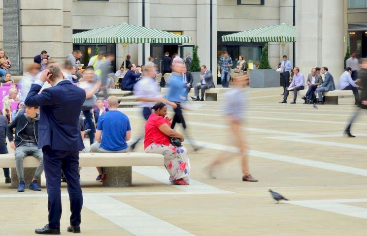 Femme migrante assise sur une place au milieu de la foule