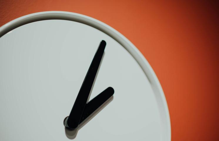 Photo en gros plan sur les aiguilles d'une horloge blanche sur un fond orange