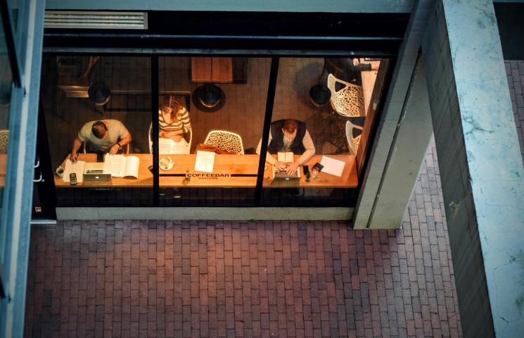 Photo vue de haut de 3 personnes en train de travailler assises dans un café