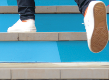 Image d'un escalier bleu et un étudiant qui marche dont on ne voit que les pieds